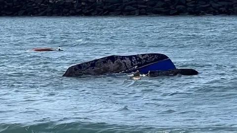 Imagen del velero volcado.