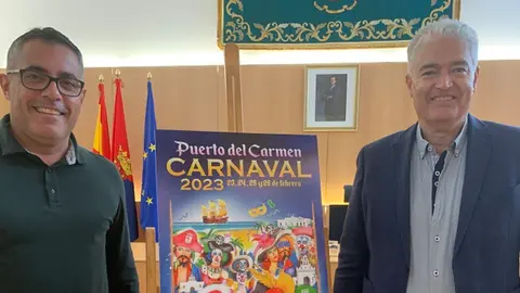 Sergio García y José Juan Cruz junto al cartel del carnaval de Puerto del Carmen 2023.
