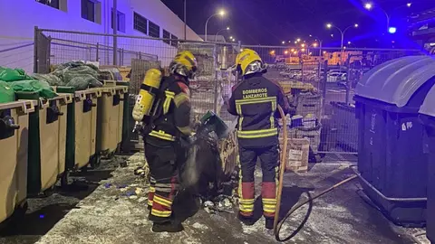 Imagen de los bomberos apagando el fuego situado en un contenedor.