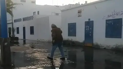 Imagen de la zona de la rotura con un vecino que trataba de sortear el charco de porquería. 