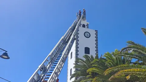 Bomberos del Consorcio retirando el elemento de madera de lo alto de la torre del Ayuntamiento de San Bartolomé.