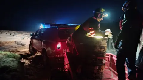 Instante en el que los bomberos amarran el bidón para su traslado