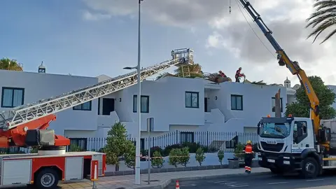 Imagen de los bomberos trabajando sobre el techo de los apartamentos