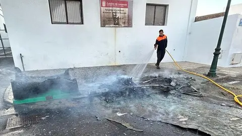 Un operario limpia tras el incendio de los contenedores en la plaza de San Roque.