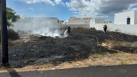 Bomberos apagando el fuego localizado en el solar.