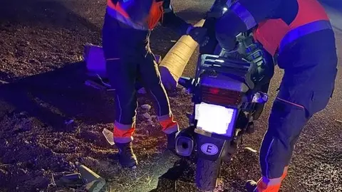 Momento en el que los bomberos retiraban la moto de la calzada.