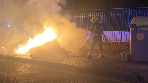 Bombero intentando apagar el fuego que estaba quemando un contenedor.