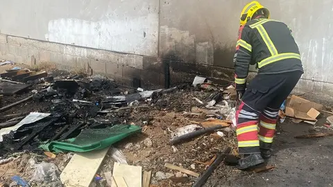 Bombero del Consorcio de Seguridad y Emergencias junto a los restos del contenedor.