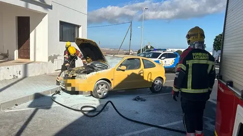Bomberos del Consorcio de Seguridad y Emergencias sofocando el fuego localizado en el motor del coche.