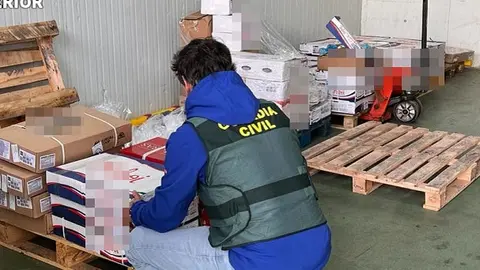 Agente de la Guardia Civil junto a la mercancía robada.