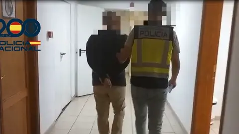Agente de la Policía Nacional acompañando al detenido.