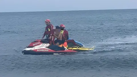 Instante en el que los bomberos trasladan al menor a la orilla