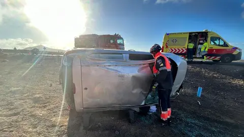 Los bomberos atendiendo al vehículo siniestrado.