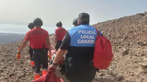 Los bomberos y la Policía Local trasladando a la persona fallecida