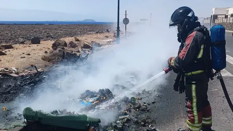 Imagen de los bomberos tratando de terminar de apagar uno de los contenedores incendiados