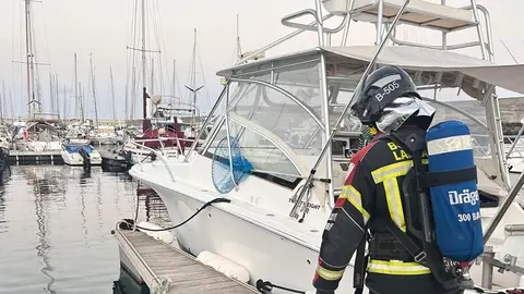 Imagen de un bombero junto a la embarcación afectada.