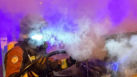 Un bombero sofoca el incendio de un contenedor.