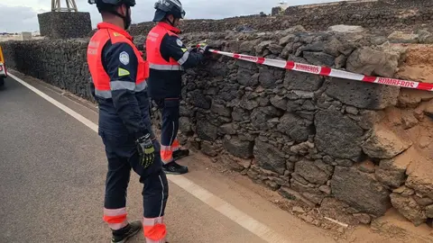 Los bomberos tras reparar el deteriorado muro.