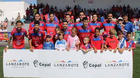 Los jugadores con parte de los aficionados al inicio del encuentro.