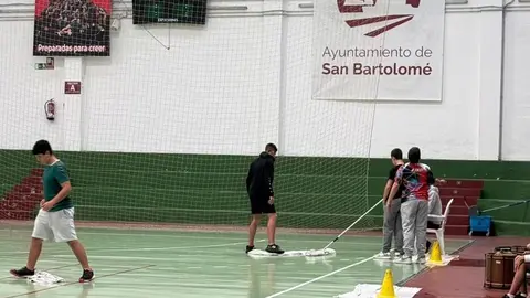 Unos niños limpiando el agua que cayó del techo del pabellón