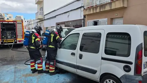 Imagen del vehículo en plena calle siendo apagado por los bomberos