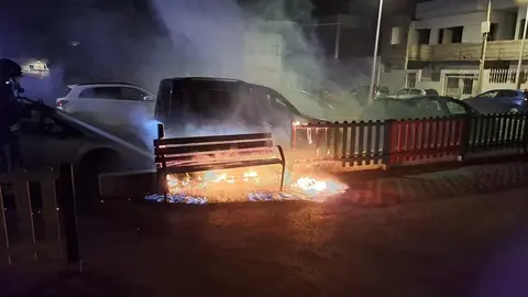 Llamas afectando al mobiliario del parque y el vehículo.