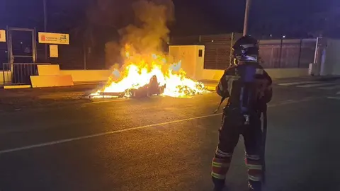 Momento en el que uno de los bomberos de guardia sofocaba el incendio de unos contenedores