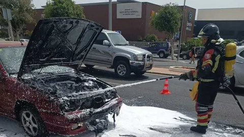 Bombero sofocando las llamas dentro del vehículo.