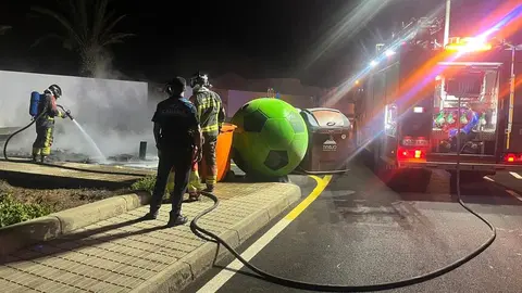 Policía Local y bomberos intentando apagar el fuego que afectaba a los contenedores.