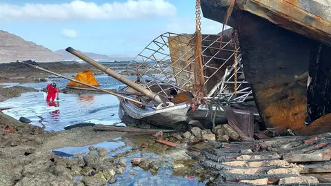Imagen de los bomberos tratando de limpiar en la medida de sus posibilidades las manchas de combustible vertidas tras el accidente.