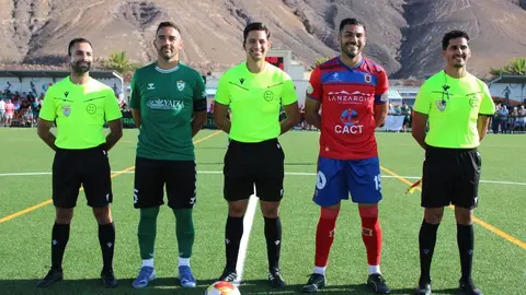 Imagen de los dos equipos con el trío arbitral.