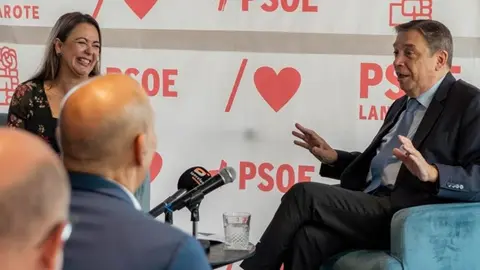 La secretaria general del PSOE sonríe durante la intervención del ministro.