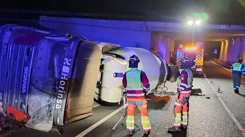 Los bomberos trabajando tras el vuelco de la hormigonera.