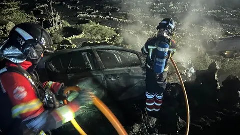 Momento en el que los bomberos tratan de apagar el fuego de uno de los veh&iacute;culos.