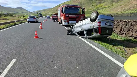 Cami&oacute;n de los bomberos junto al veh&iacute;culo volcado.