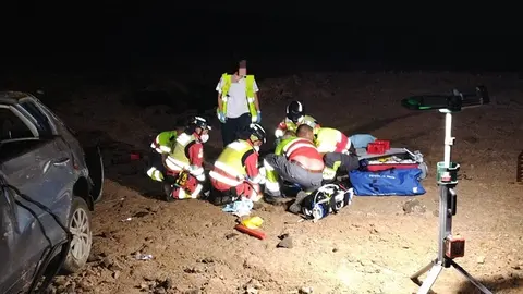 Sanitarios y bomberos atendiendo a uno de los accidentados que se encontraba junto al veh&iacute;culo.