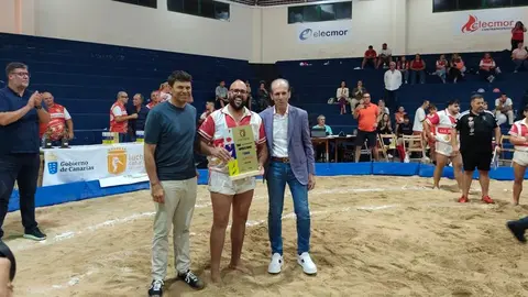 El representante de Caja 7 con el presidente de la Federaci&oacute;n Canaria de Lucha entregando el galard&oacute;n al capit&aacute;n del equipo vencedor