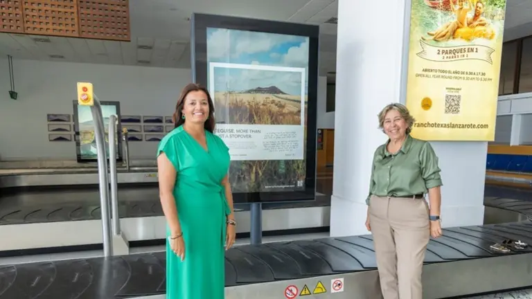 Olivia Duque y Rita Hern&aacute;ndez junto a un cartel promocional de Teguise.