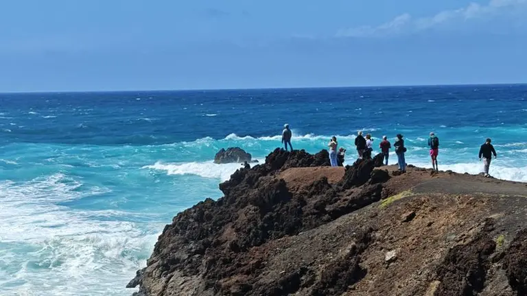 Imagen de personas que tratan de acercarse lo m&aacute;ximo al mar para fotografiar las olas