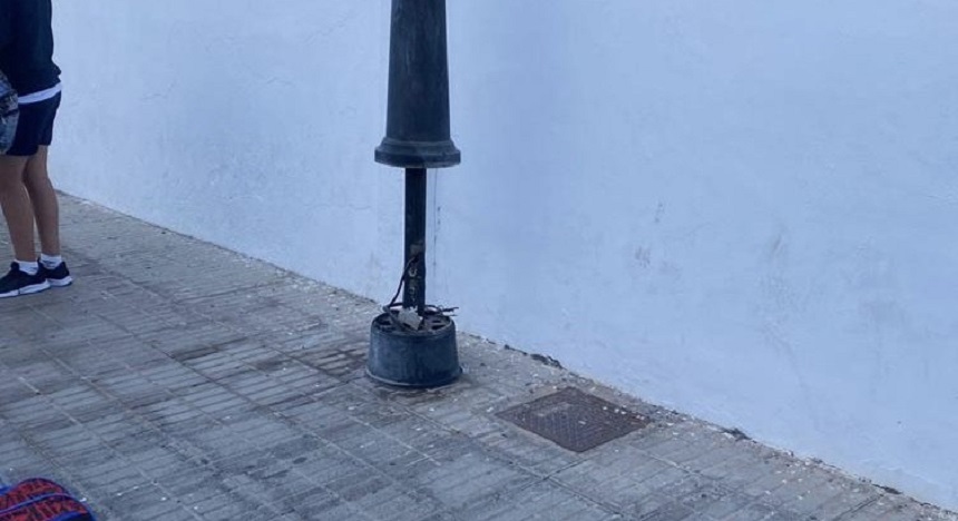 Imagen de una farola en mal estado cerca de un colegio.
