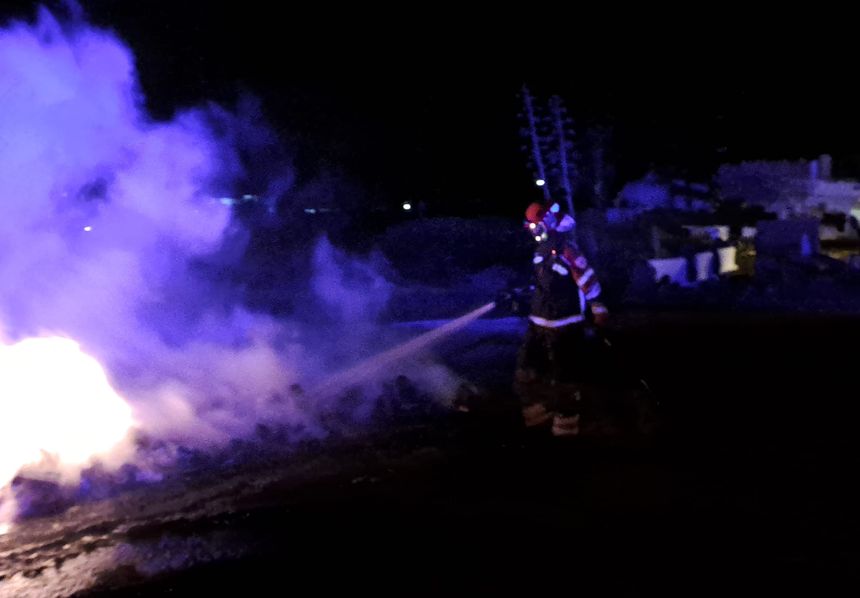 Un bombero sofoca el incendio en uno de los contenedores.