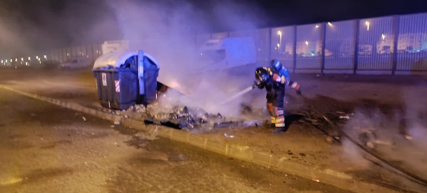 Bombero apagando un contenedor calcinado.