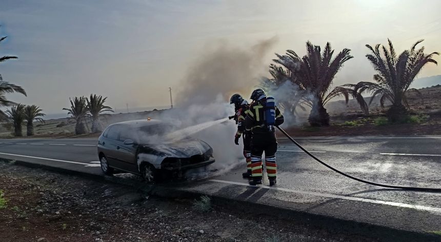 Los bomberos sofocando el incendio del vehículo en la carretera