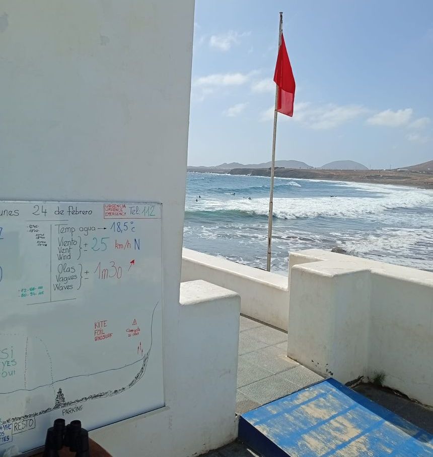 Imagen del puesto de vigilancia de la playa de La Garita, en Arrieta, con bandera roja y gente dentro del agua
