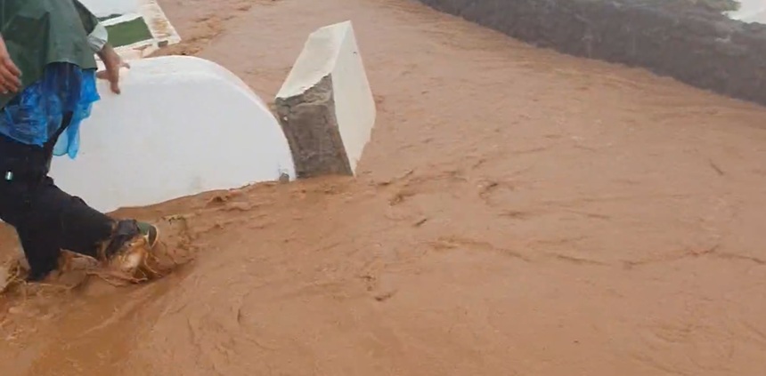 Uno de los trabajadores de un hotel de Costa Teguise tratando de escapar del barranco que se ha creado y que caía con notable fuerza.