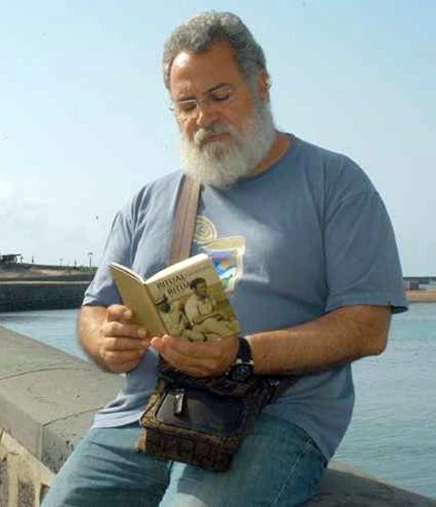 Félix Hormiga sentado en el puente de las bolas leyendo un libro.