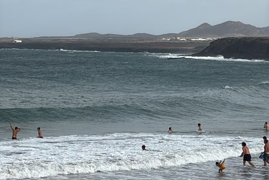 La embarcación llegando a la costa mientras la gente se baña en la playa de La Garita